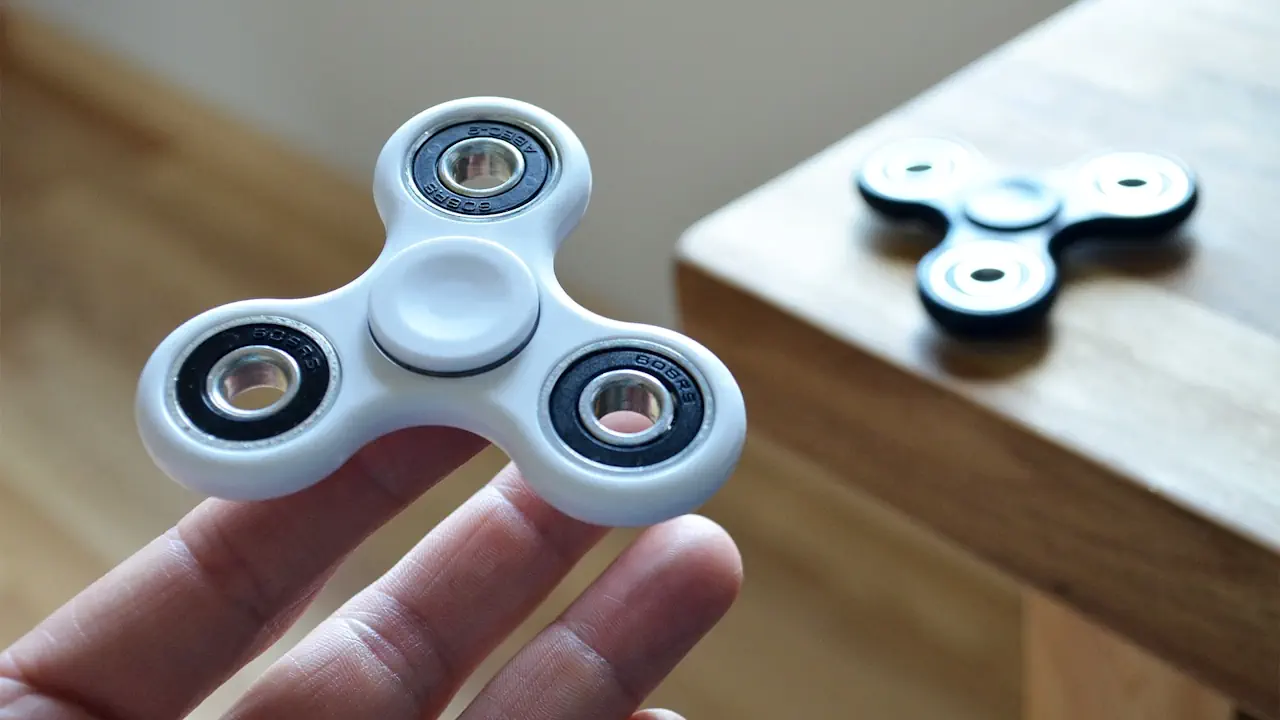 Un hand spinner blanc posé sur un doigt.