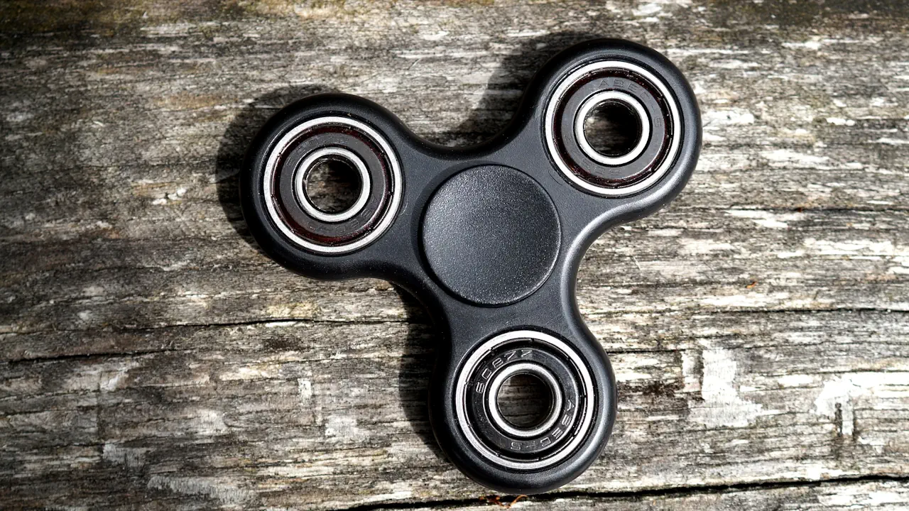 Un hand spinner noir posé sur une table en bois.